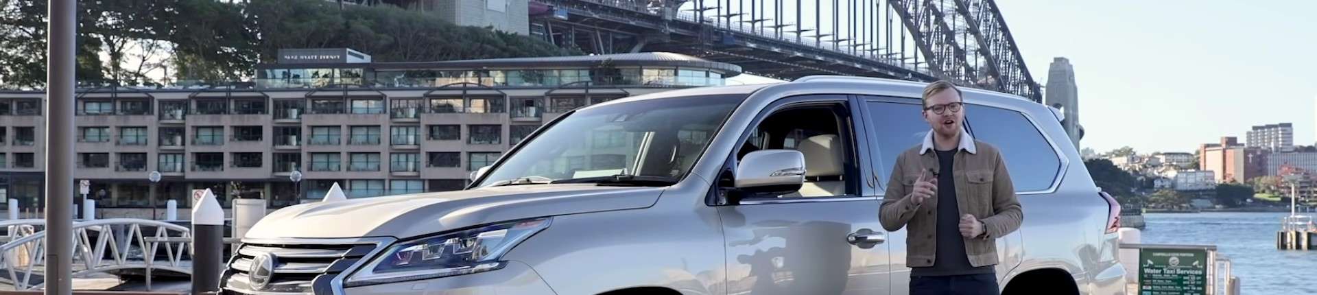 Presenter standing next to a Lexus SUV with Sydney Harbour Bridge in the background