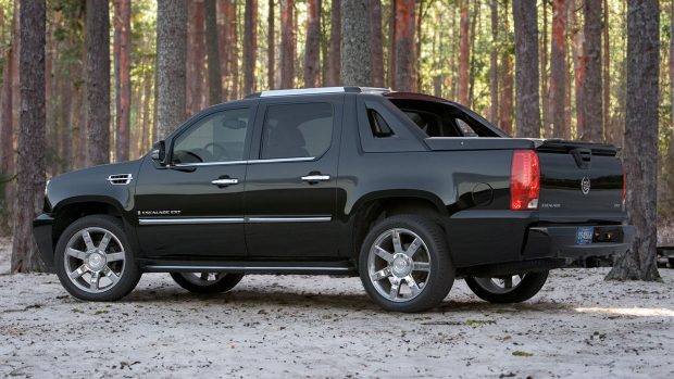 Rear left three quarter image of a 2009 Cadillac Escalade EXT pick-up truck in a wooded space