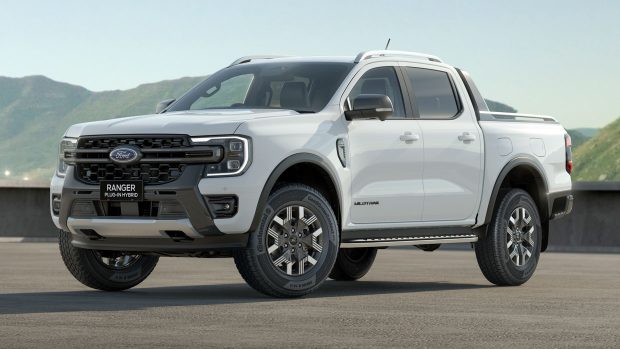 A Ford Ranger Wildtrak poke-in hybrid ute in white in opposition to mountains and a blue sky