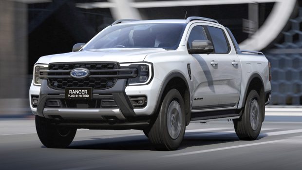 A Ford Ranger Wildtrak poke-in hybrid ute in white riding down a city road with a building within the background