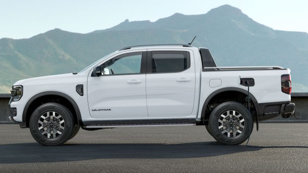 A Ford Ranger Wildtrak poke-in hybrid ute in profile in white in opposition to mountains and a blue sky with cost door birth