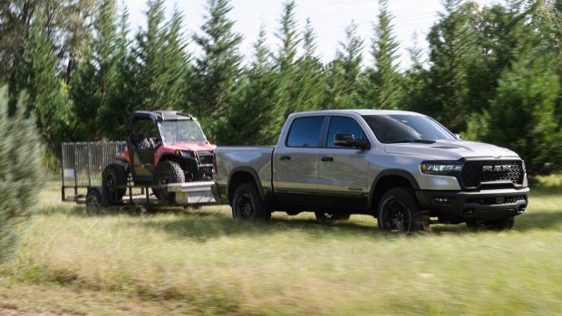 2025 Ram 1500 Rebellion towing trailer by grass